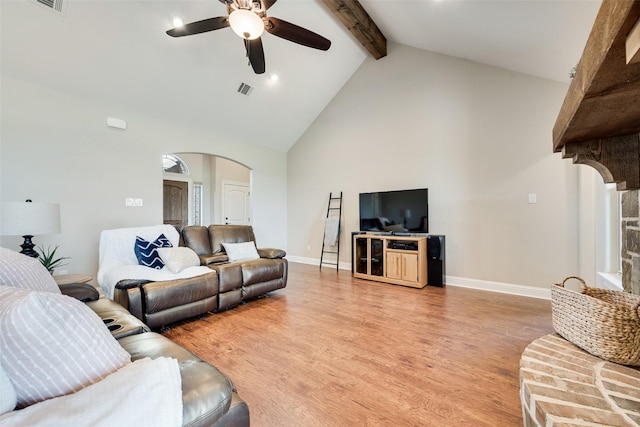 living area with beam ceiling, ceiling fan, high vaulted ceiling, arched walkways, and light wood-style flooring