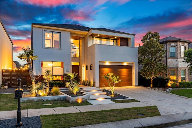 contemporary house featuring concrete driveway, a garage, a balcony, and stucco siding