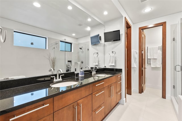bathroom with double vanity, a sink, a stall shower, and tile patterned flooring