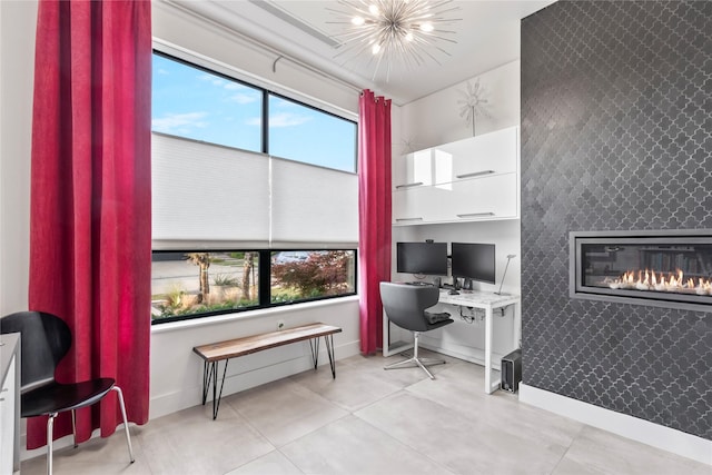 office space with baseboards, a glass covered fireplace, an accent wall, and a wealth of natural light