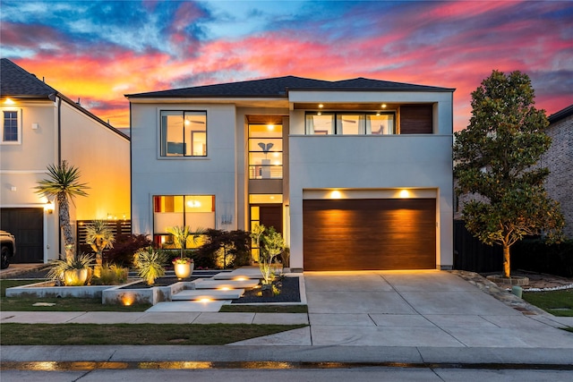 view of front of home with an attached garage, driveway, a balcony, and stucco siding