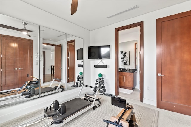 exercise room with baseboards, ceiling fan, and light colored carpet