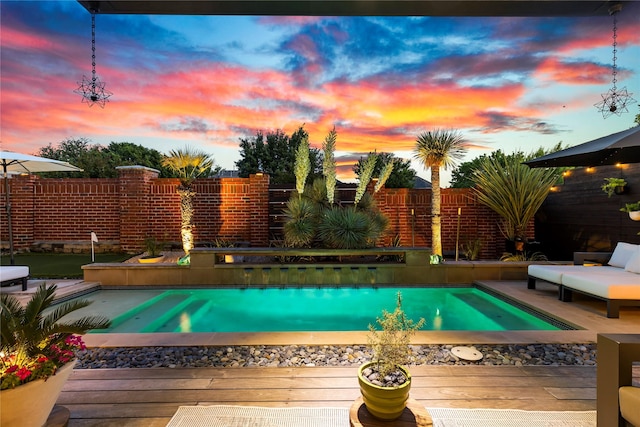 pool at dusk featuring a fenced in pool, fence private yard, and a deck