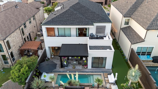 rear view of property featuring a shingled roof, a fenced backyard, and stucco siding