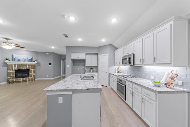 kitchen featuring visible vents, white cabinetry, a sink, light wood-style flooring, and stainless steel appliances