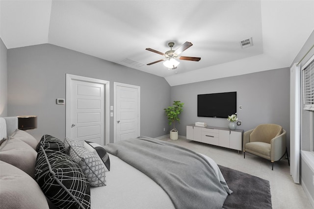 carpeted bedroom featuring a ceiling fan, vaulted ceiling, and visible vents