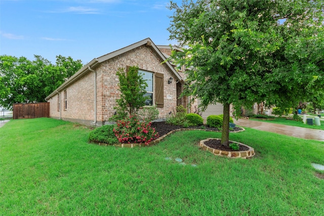 view of home's exterior with a yard, brick siding, fence, and concrete driveway