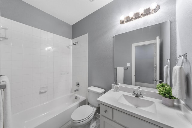 full bath featuring toilet, a textured wall, tub / shower combination, and vanity