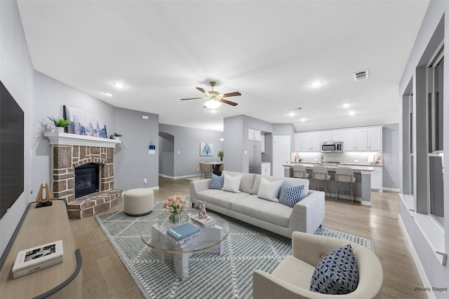 living room featuring a ceiling fan, visible vents, baseboards, light wood-style floors, and recessed lighting