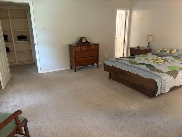 bedroom with baseboards, a spacious closet, and light carpet