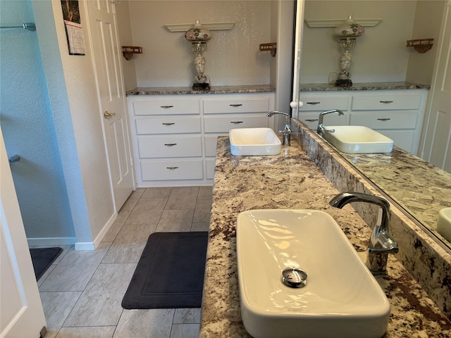 full bath with double vanity, baseboards, and a sink