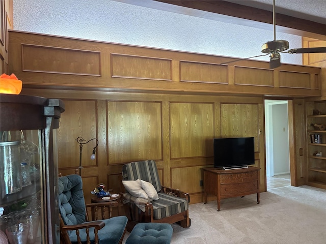 living area featuring wooden walls, ceiling fan, and light carpet