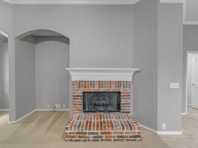 living room with crown molding, baseboards, a fireplace, and arched walkways