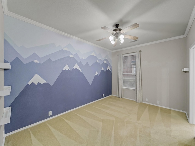 spare room featuring ceiling fan, visible vents, baseboards, ornamental molding, and carpet flooring