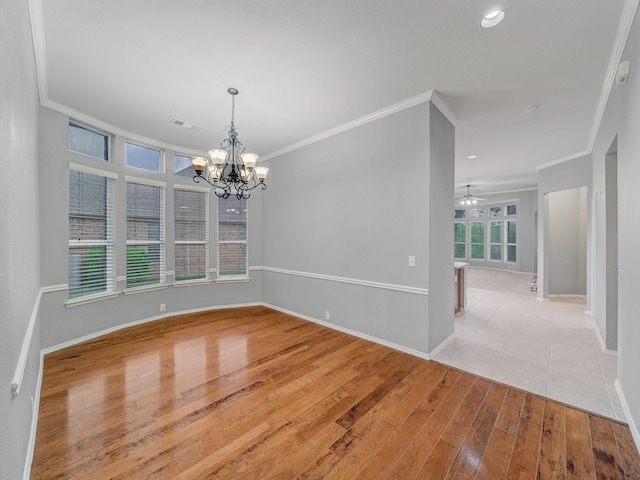 empty room featuring ceiling fan with notable chandelier, baseboards, wood finished floors, visible vents, and ornamental molding