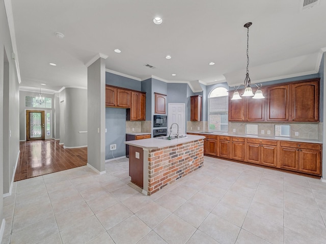 kitchen featuring crown molding, black microwave, a sink, light countertops, and a chandelier