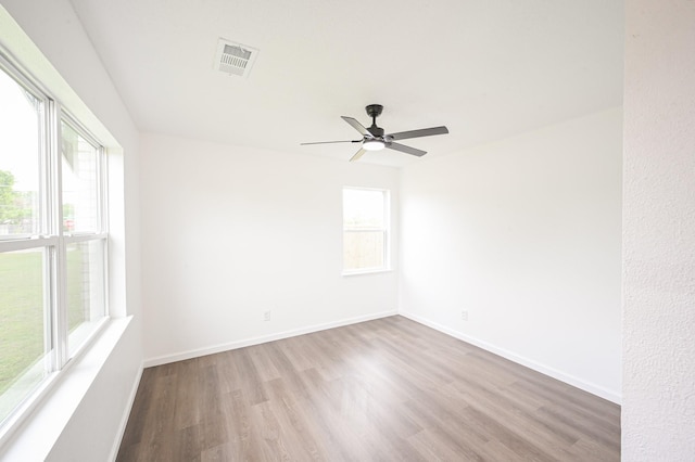 spare room with baseboards, ceiling fan, visible vents, and wood finished floors