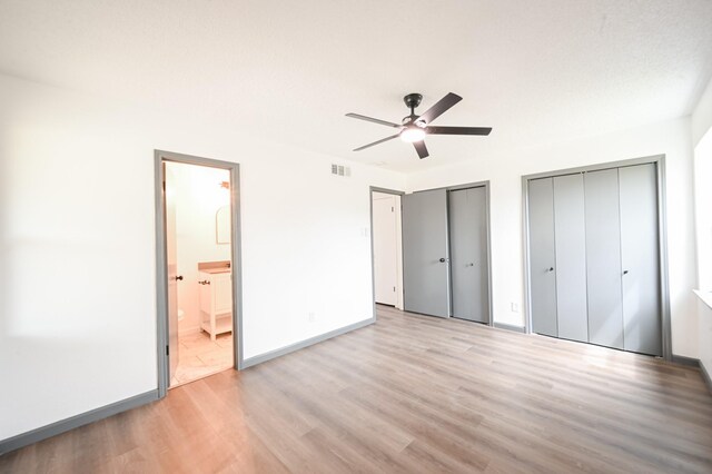 8511 Strathmore Dr, Dallas, TX 75238 - unfurnished bedroom with light wood-style flooring, two closets, baseboards, ensuite bathroom, and ceiling fan