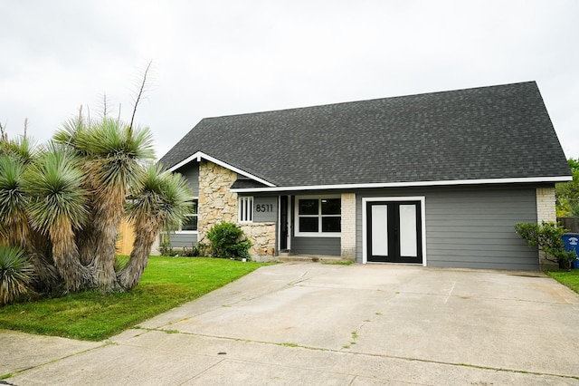 view of front of house featuring french doors, roof with shingles, a front yard, and stone siding