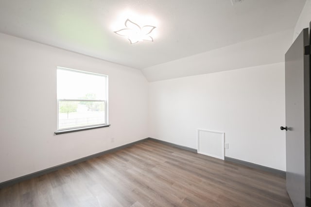 additional living space with baseboards, dark wood-style flooring, and lofted ceiling