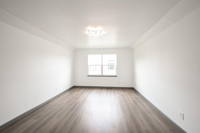 spare room with baseboards and wood finished floors