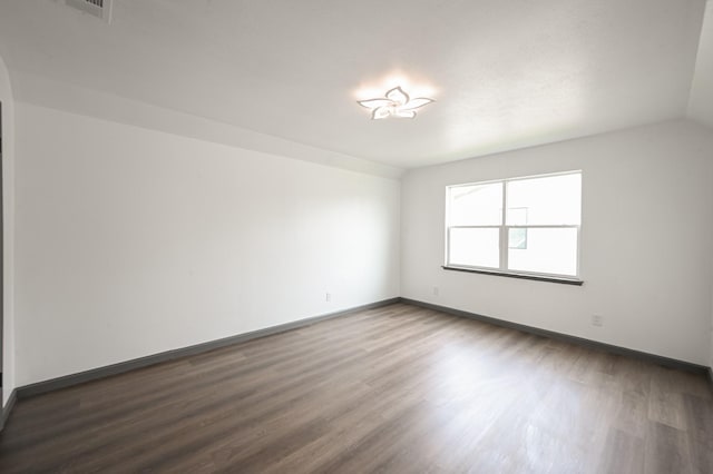 empty room featuring baseboards and dark wood-style flooring