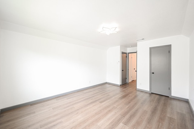 empty room with light wood-style floors, baseboards, and visible vents