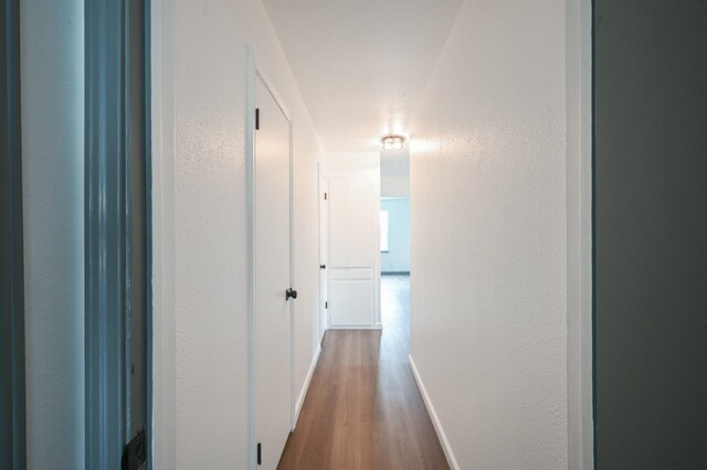 8511 Strathmore Dr, Dallas, TX 75238 - corridor with a textured wall, dark wood finished floors, and baseboards