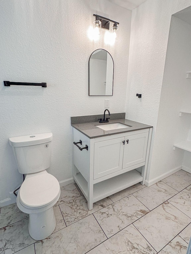bathroom featuring toilet, baseboards, marble finish floor, and vanity