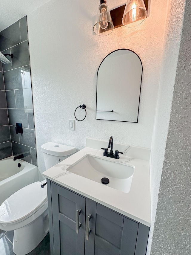 bathroom with vanity, a textured wall, shower / bathing tub combination, and toilet