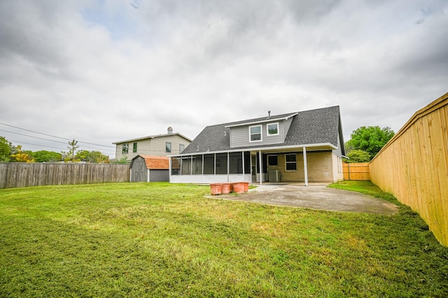 back of property featuring a patio, a fenced backyard, roof with shingles, a sunroom, and a storage unit
