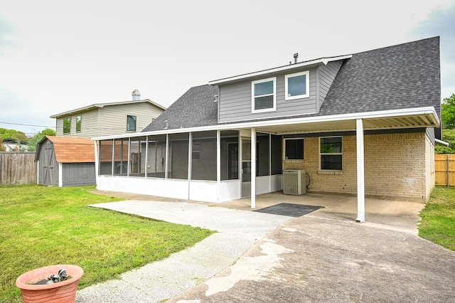 back of property with central air condition unit, roof with shingles, a shed, and a sunroom