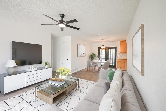 8511 Strathmore Dr, Dallas, TX 75238 - living room featuring light wood finished floors, a ceiling fan, a textured ceiling, and baseboards