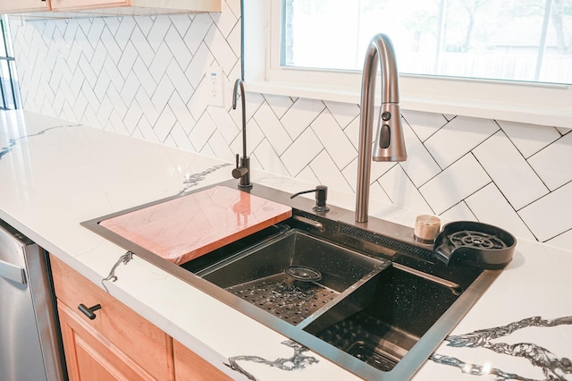 interior details featuring light stone counters, a sink, backsplash, and light brown cabinetry