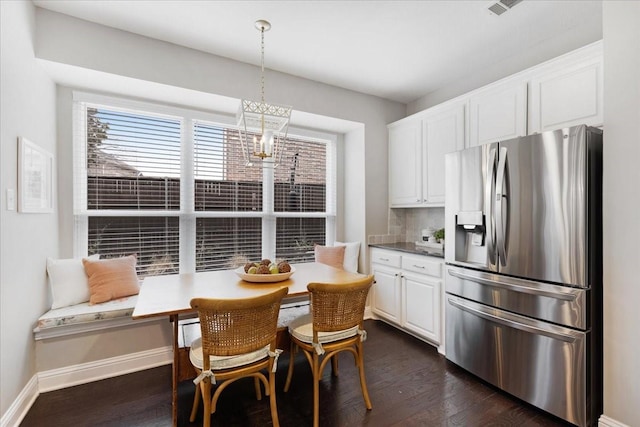 4460 Connemara Dr, Frisco, TX 75034 - kitchen with dark wood-style flooring, baseboards, stainless steel fridge, white cabinets, and hanging light fixtures