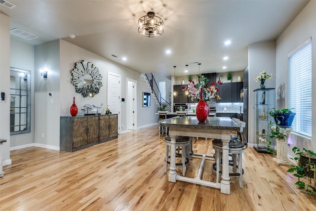 11955 Hoblitzelle Dr, Dallas, TX 75243 - kitchen with modern cabinets, appliances with stainless steel finishes, light wood finished floors, a center island with sink, and decorative backsplash