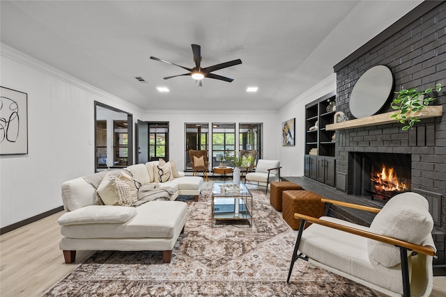 living area with ceiling fan, a brick fireplace, built in features, baseboards, and wood finished floors