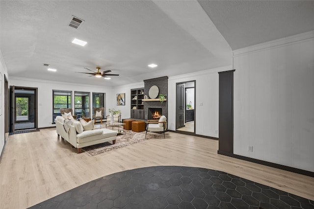 living room featuring crown molding, a ceiling fan, light wood-style flooring, and visible vents