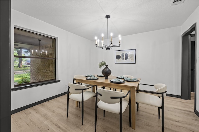 dining area with baseboards, an inviting chandelier, light wood-style flooring, and visible vents