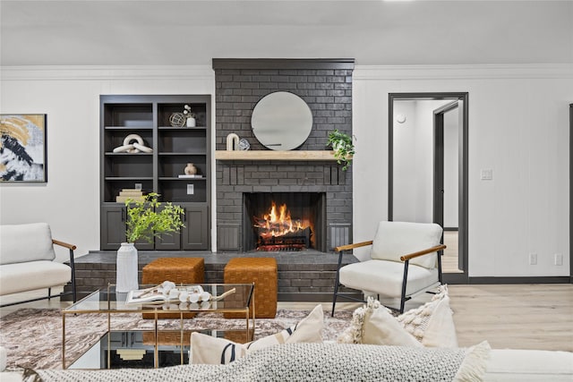 living area with crown molding, built in features, a brick fireplace, and wood finished floors