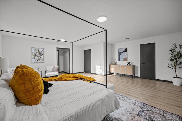 bedroom with visible vents, light wood-style flooring, and baseboards