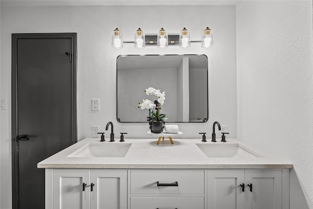bathroom featuring double vanity, a sink, and a textured wall