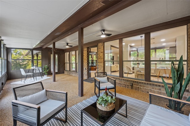 sunroom / solarium featuring a ceiling fan, an outdoor living space, and beamed ceiling