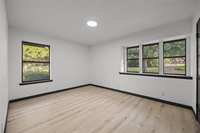 unfurnished room featuring baseboards, a wealth of natural light, and light wood-style flooring