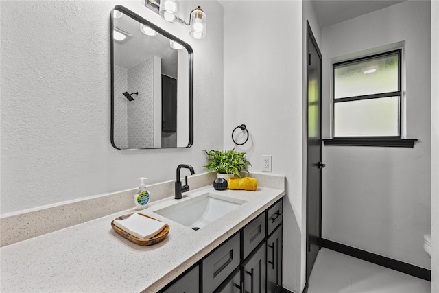 bathroom with toilet, a textured wall, and vanity