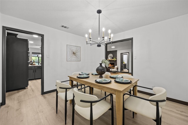 dining room with an inviting chandelier, baseboards, light wood-type flooring, and visible vents