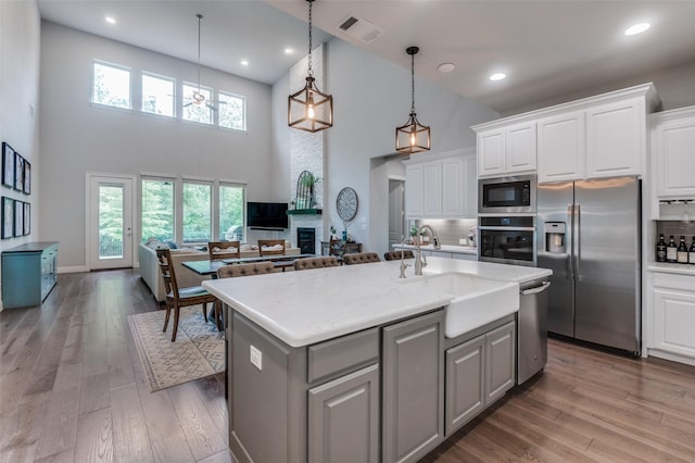 kitchen with visible vents, decorative backsplash, a towering ceiling, a sink, and stainless steel appliances