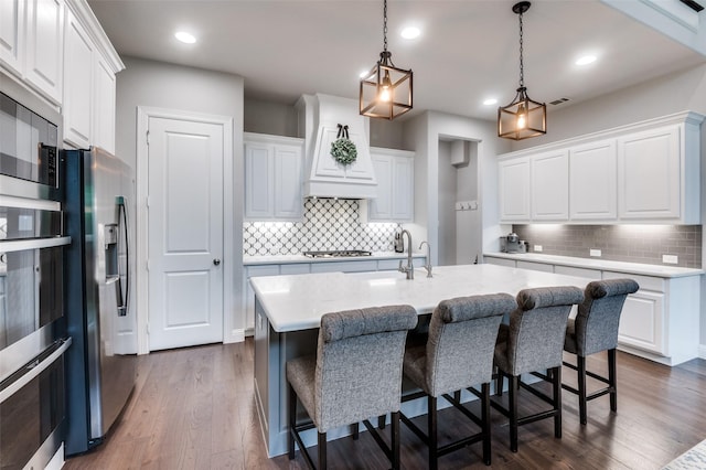 kitchen featuring a sink, backsplash, dark wood-style floors, and stainless steel appliances