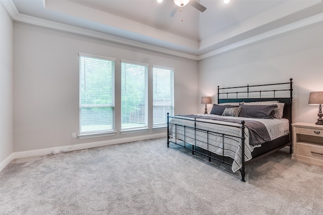 carpeted bedroom featuring baseboards, ornamental molding, a raised ceiling, and a ceiling fan