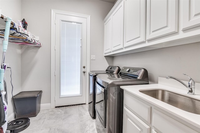 laundry area with baseboards, a sink, cabinet space, and washing machine and dryer